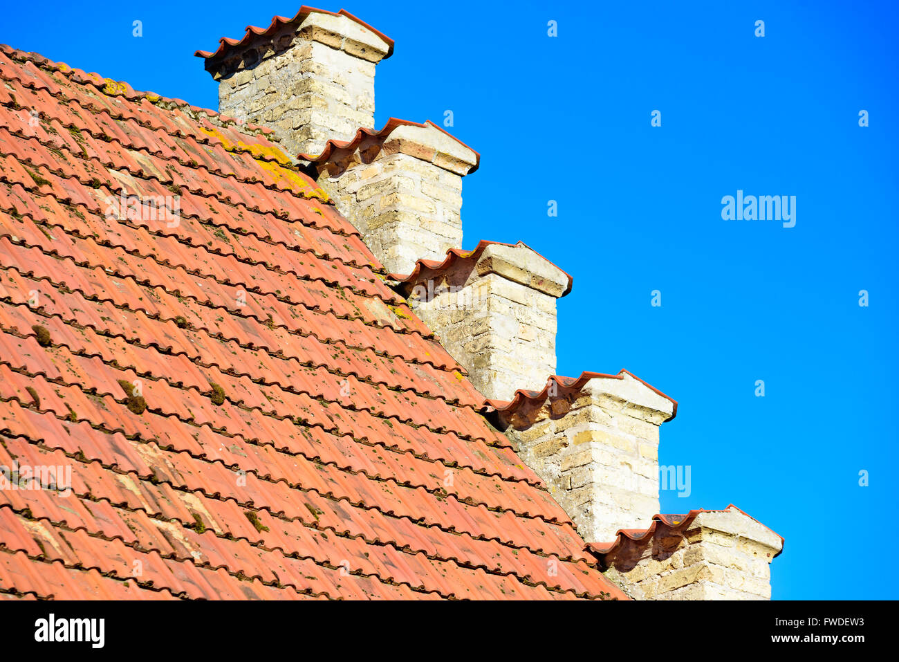 Incantevoli dettagli architettonici di una vecchia casa di mattoni dove la facciata di colore giallo incontra il tetto di tegole rosse e. Foto Stock