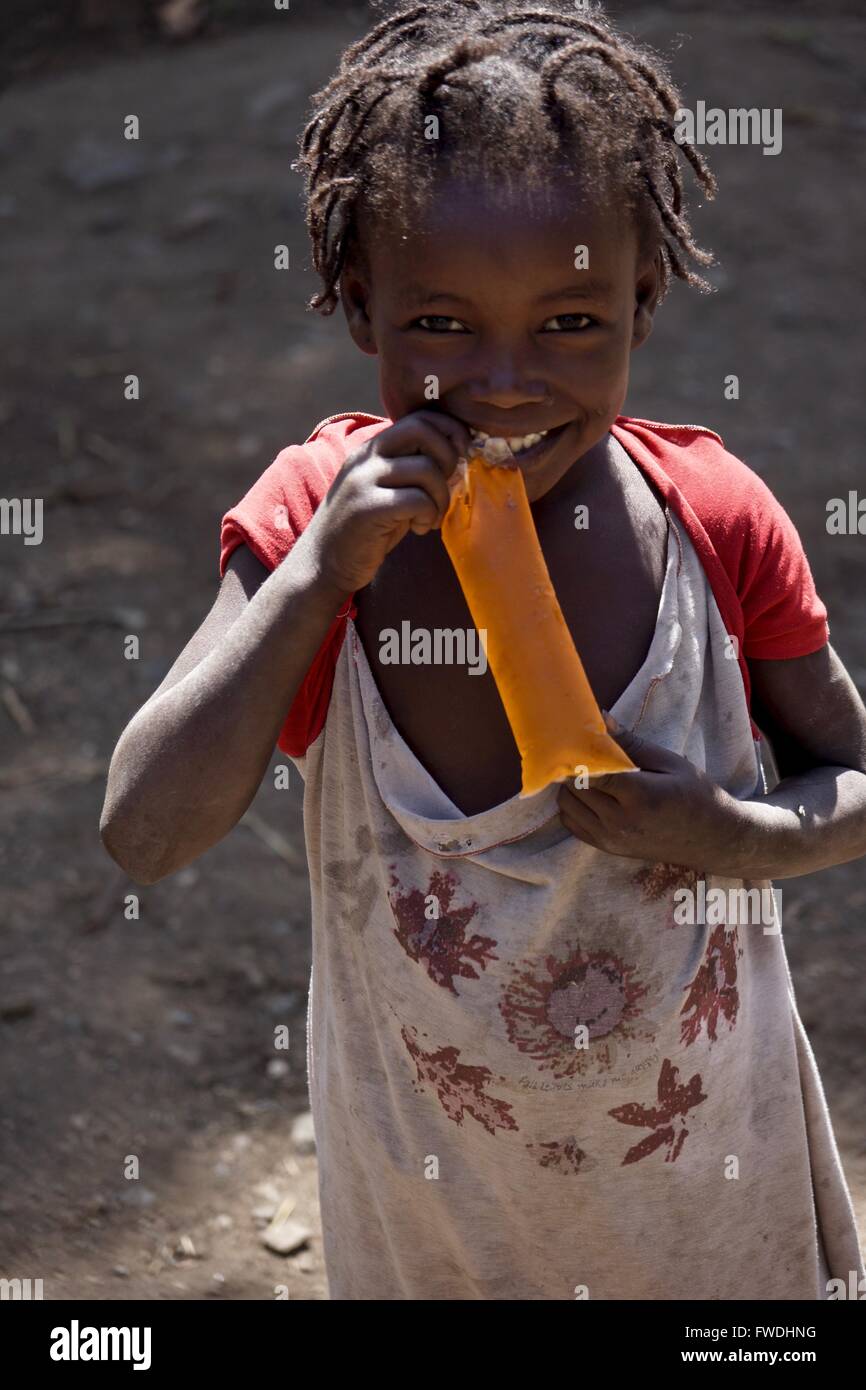 Una giovane ragazza in Etiopia è eccitato per ottenere una bevanda dolce. Foto Stock