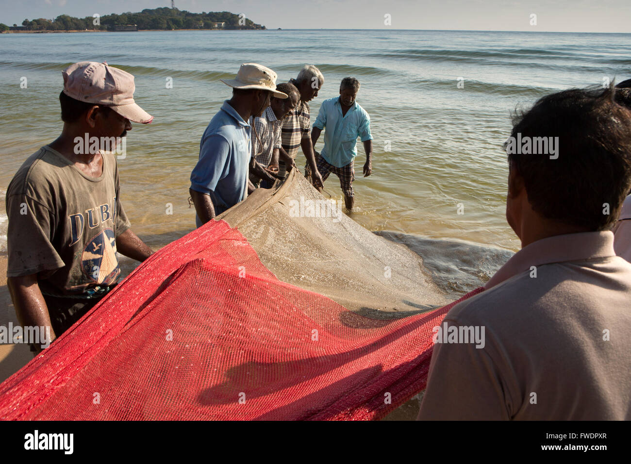 Sri Lanka, Trincomalee, olandese Bay, pescatori pesca salpamento in ferro di cavallo rosso net da riva Foto Stock