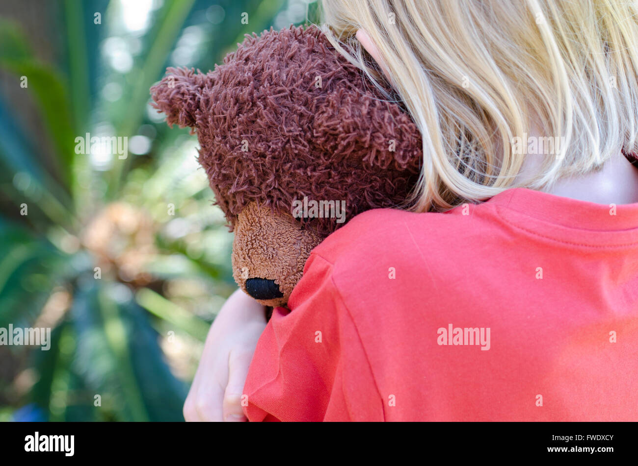 Bambina abbracciando il suo orsacchiotto marrone vicino Foto Stock
