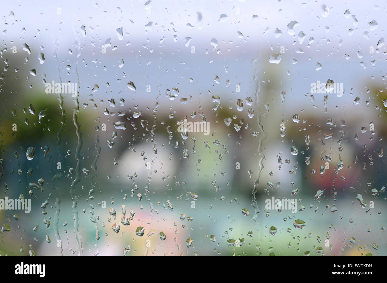 Gocce di pioggia sulla finestra con giardino e mare in background Foto Stock
