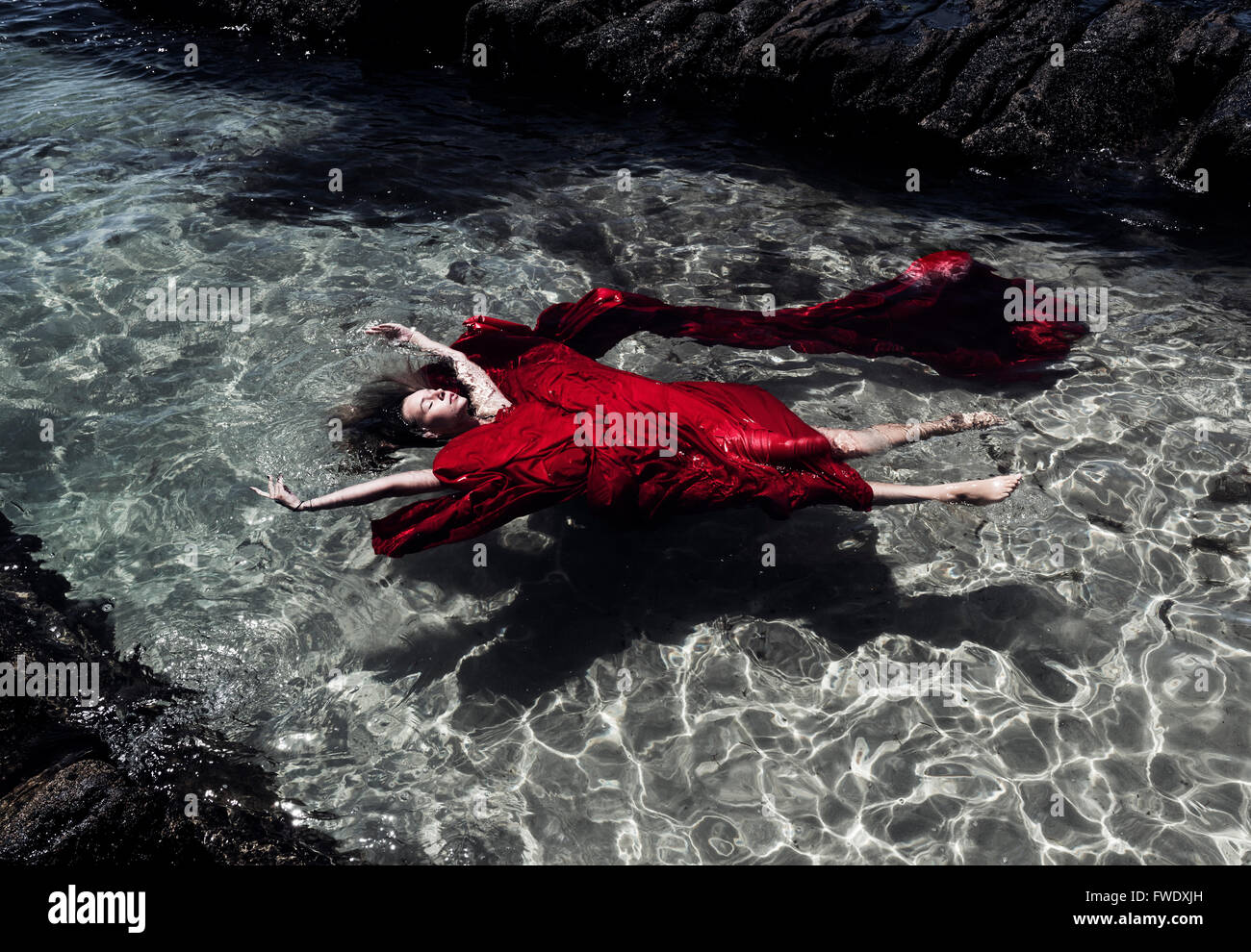 Donna in panno rosso galleggia nell'acqua. Foto Stock