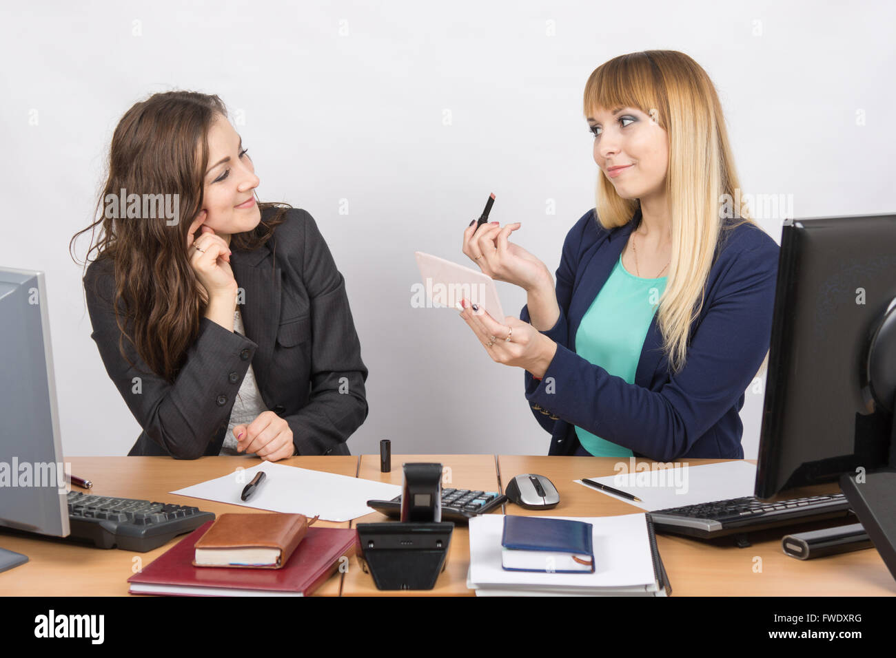 Office il dipendente dimostra il rossetto collega alla scrivania Foto Stock