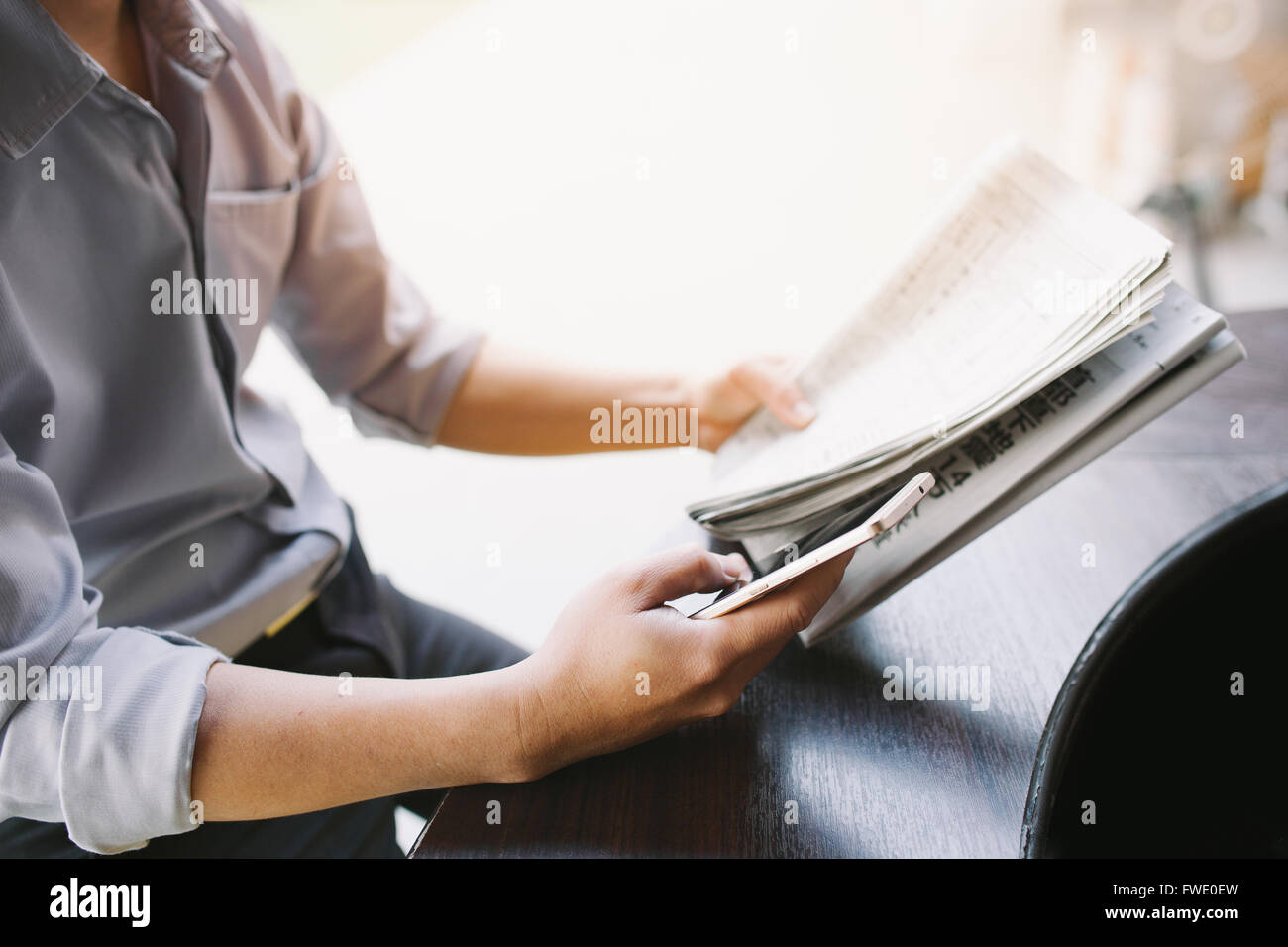 Uomo di mani tenendo il giornale e utilizza lo smartphone per online . Foto Stock