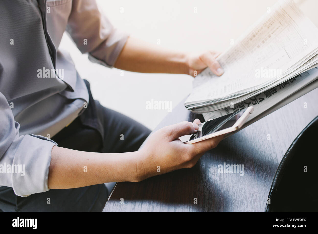 Uomo di mani tenendo il giornale e utilizza lo smartphone per online . Foto Stock