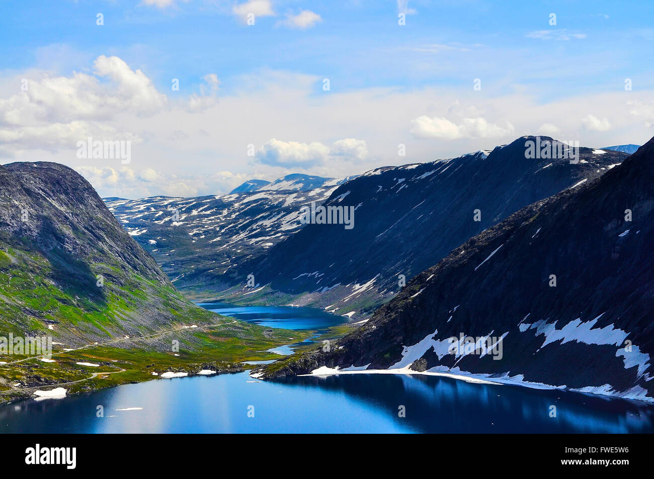 Luminosa e vivace immagine colorata con cielo blu, il bianco delle nuvole, mare blu acqua e buio possenti montagne. Erba verde il coperchio m Foto Stock