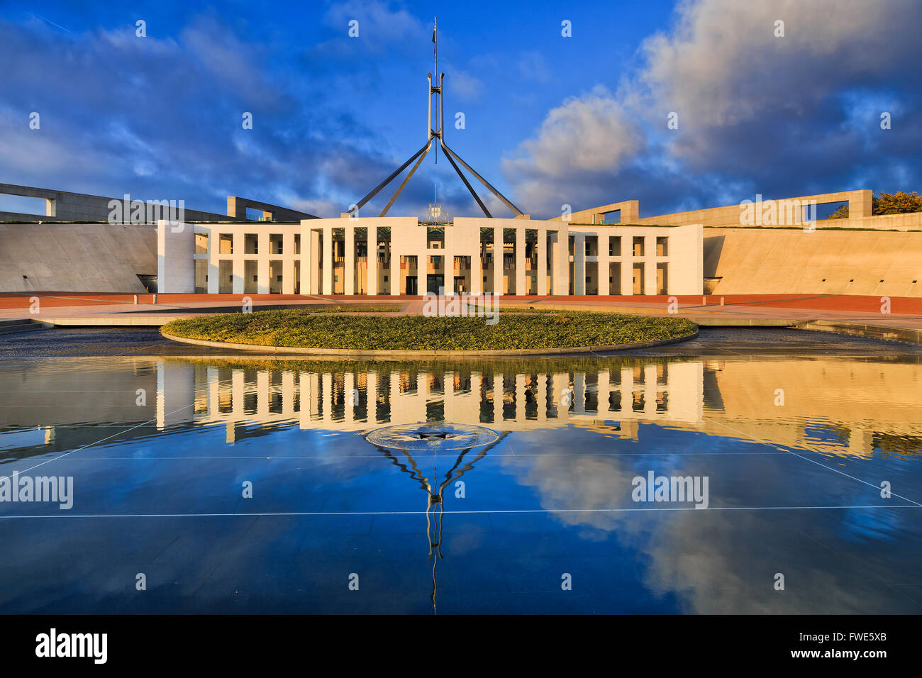 La facciata della nuova casa del parlamento di Australia a Canberra con alta bandiera su un pennone con la riflessione in stil acqua del Capitol hi Foto Stock