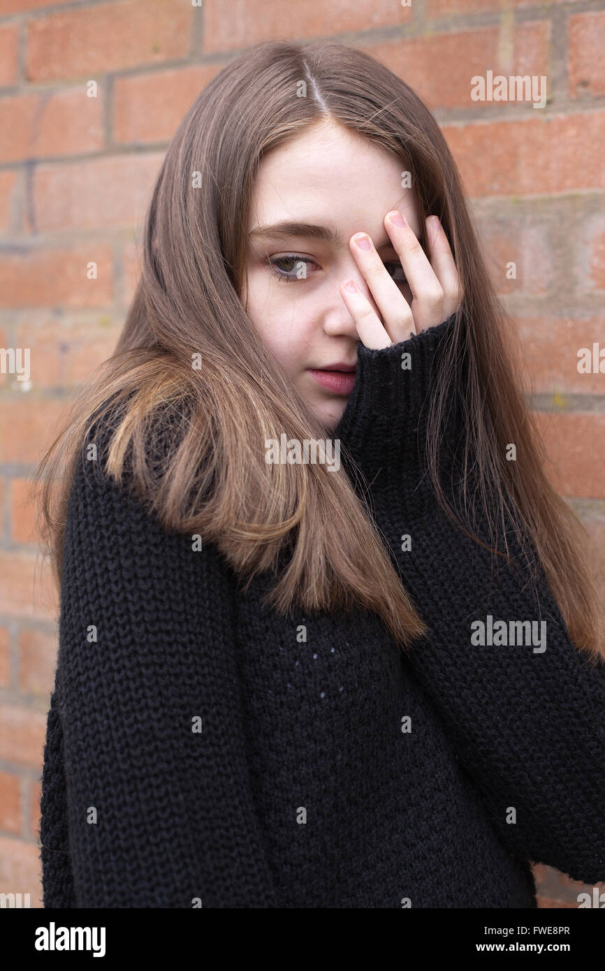 Ragazza giovane con la mano che copre il volto alla ricerca spaventati Foto Stock