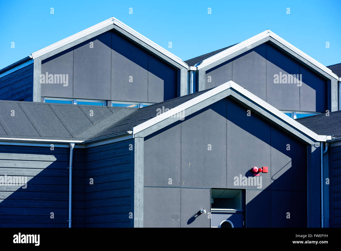 Grigio di ripetizione creste o gables sulle case. Red il campanello di allarme su un timpano. Foto Stock