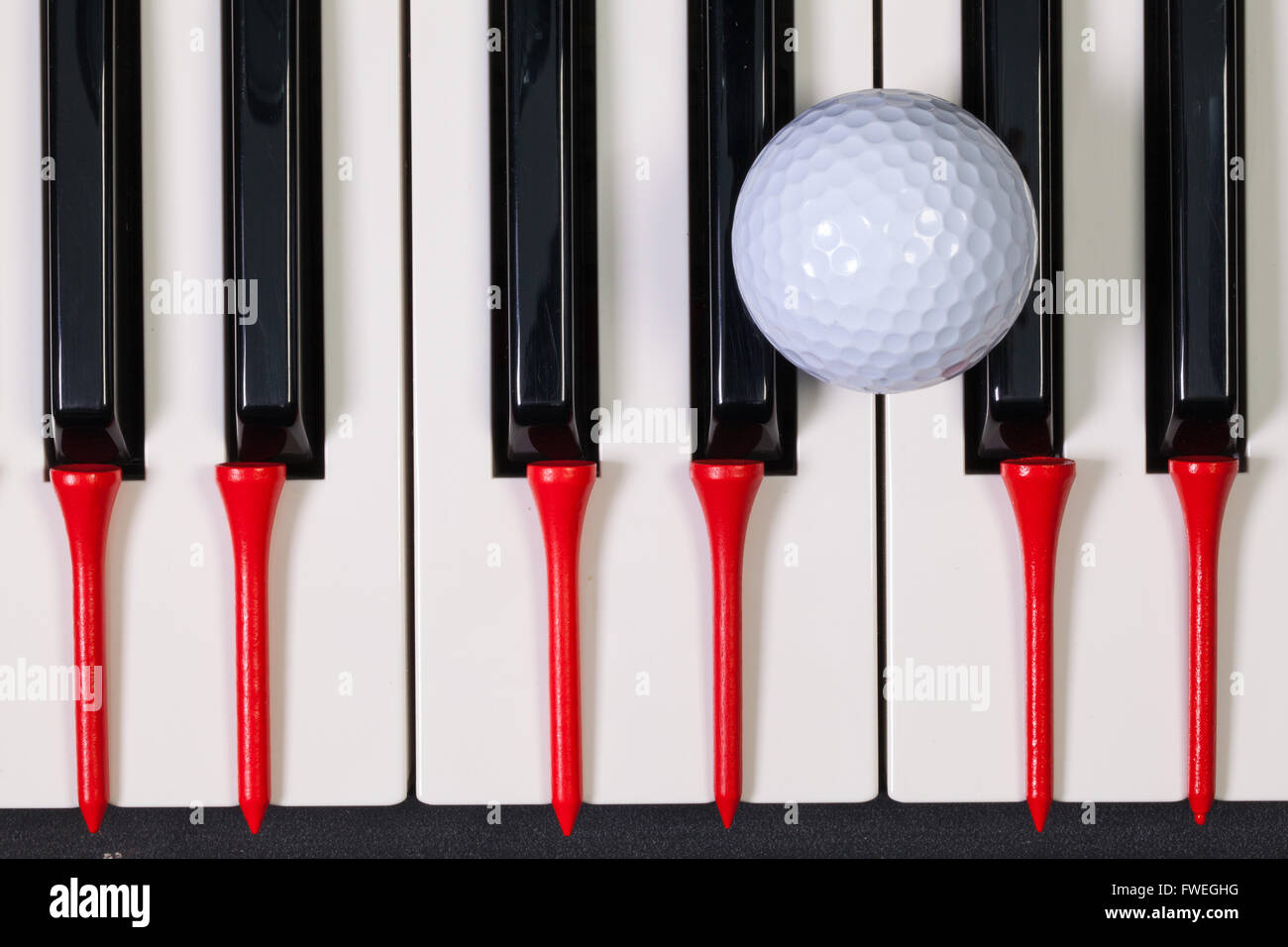 Virtuosi di gioco - Una tastiera di pianoforte e differenti palline da golf e tee di legno Foto Stock