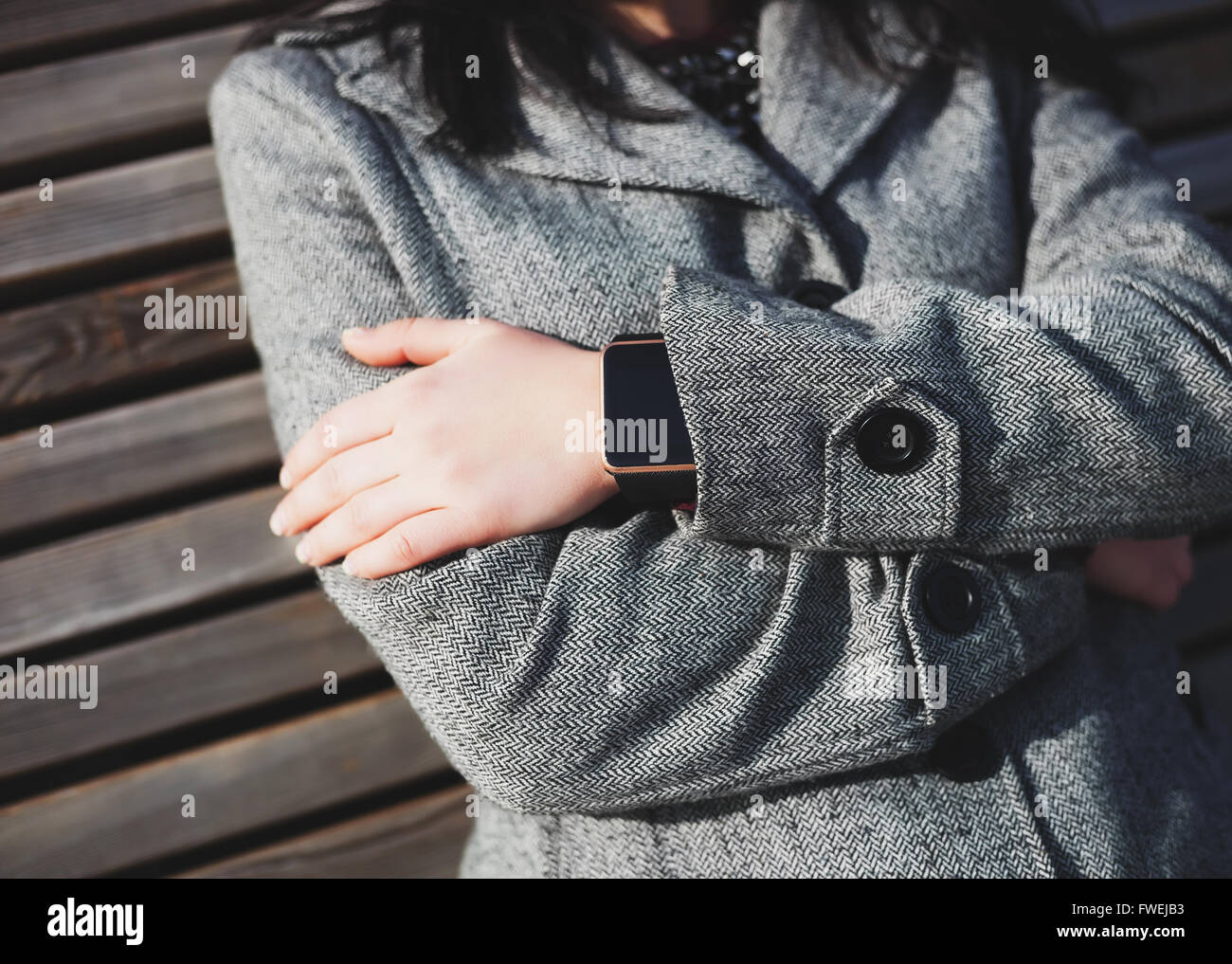 Ragazza seduta sul banco indossando moderne smart orologio da polso. Questa persona è sempre collegato al social media e internet addirittura seduta nel parco. Foto Stock