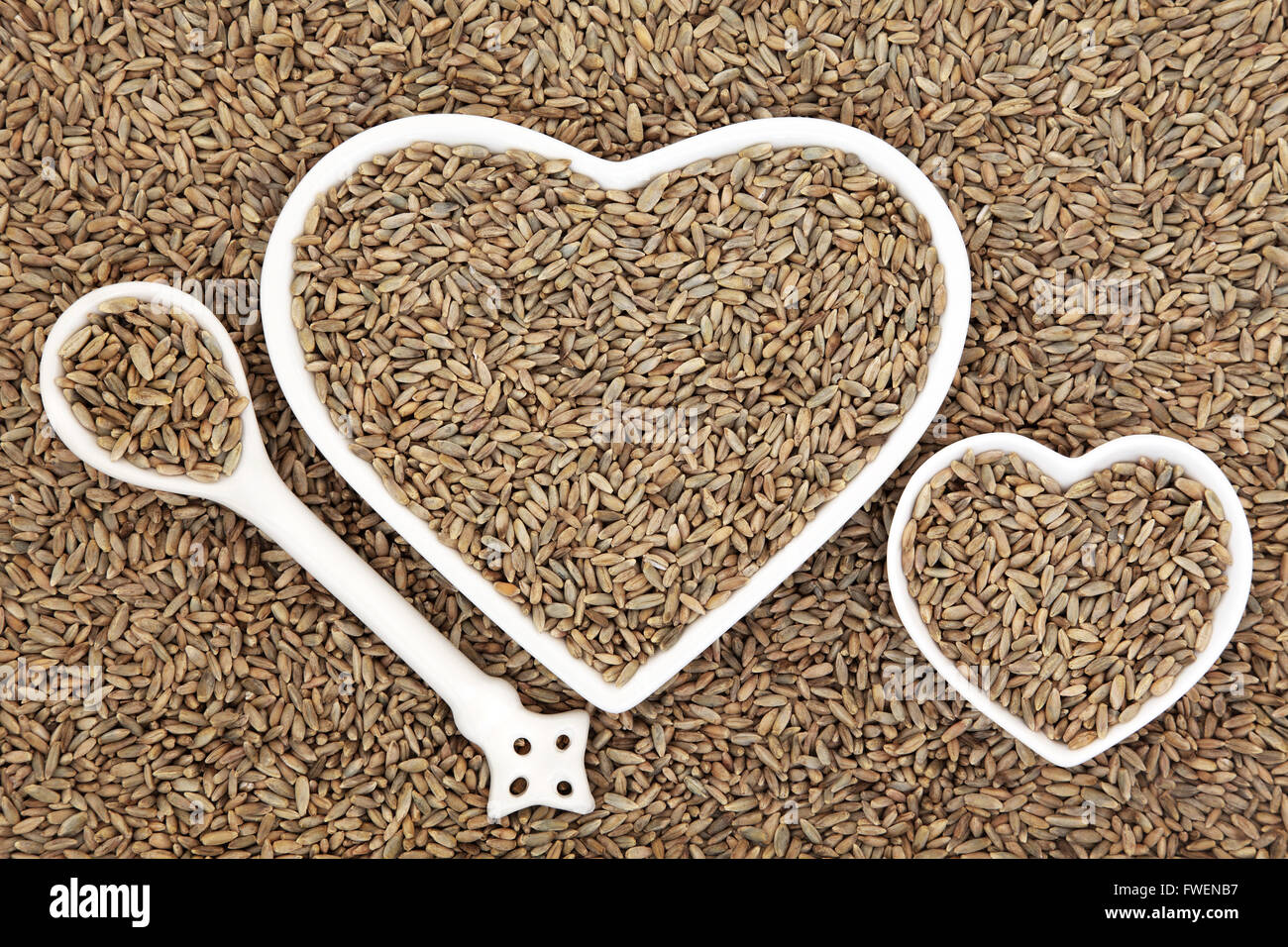 Segale grano in a forma di cuore e di bocce porcellana cucchiaio formando un abstract background. Foto Stock