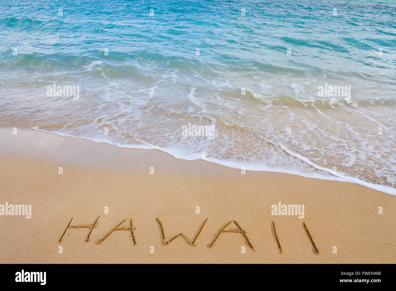 La parola Hawaii è scritta nella sabbia di questa spiaggia come onde venire a lavare via. Si tratta di una vacanza immagine raffigurante il trop Foto Stock