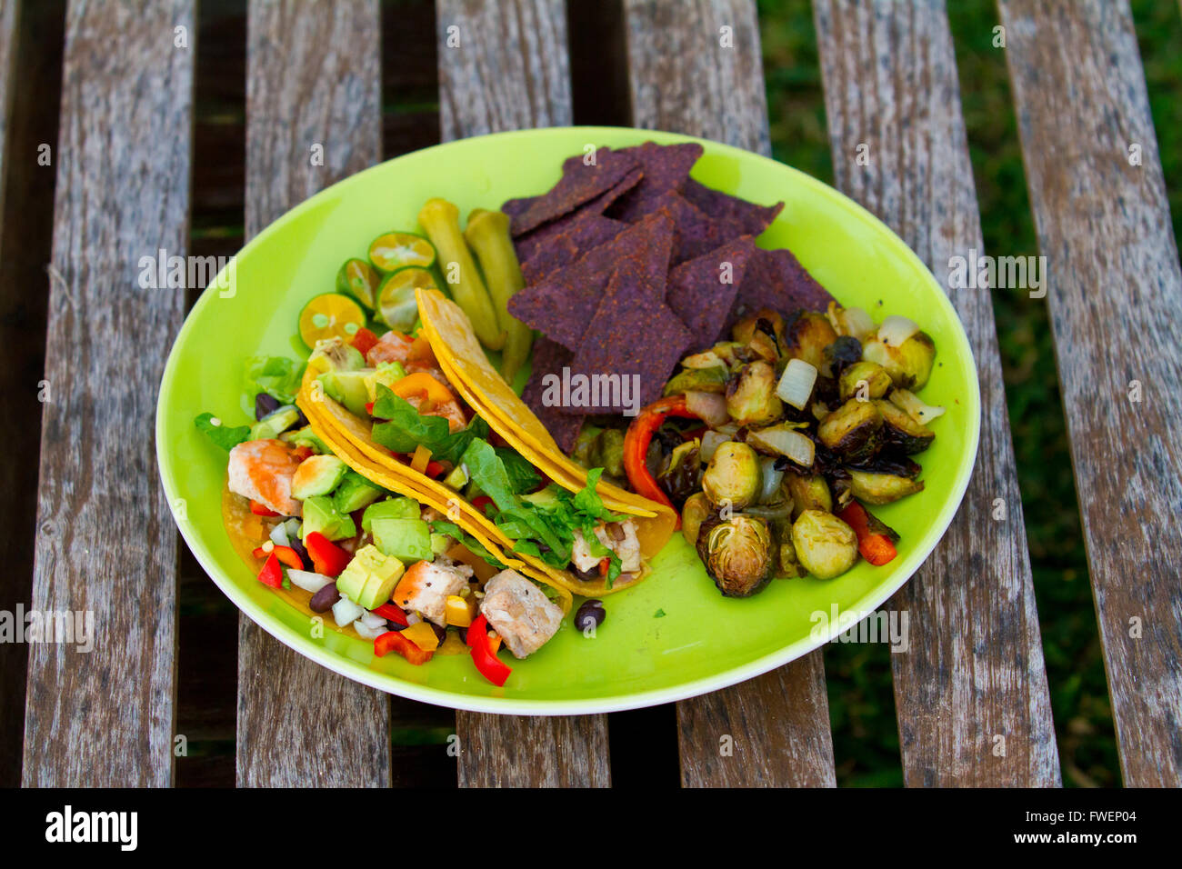Questo semplice pasto di pesce tacos è servita con alcune verdure arrosto e chip su una piastra verde nelle Hawaii. Foto Stock
