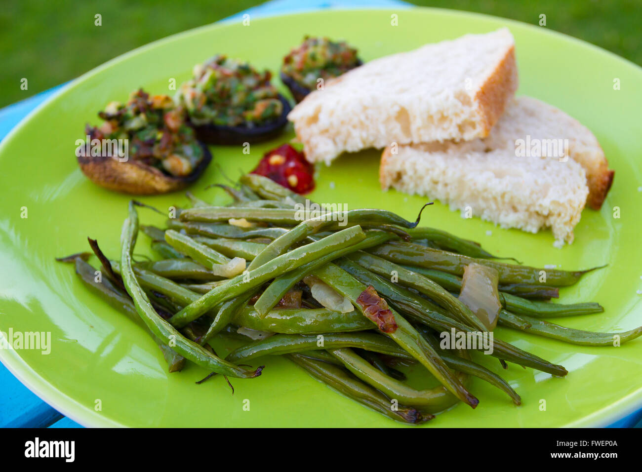 Questo pasto gourmet di Funghi ripieni e fagioli verdi servita su una piastra verde con un po' di pane bianco. Questa è la cena ma l'IMA Foto Stock