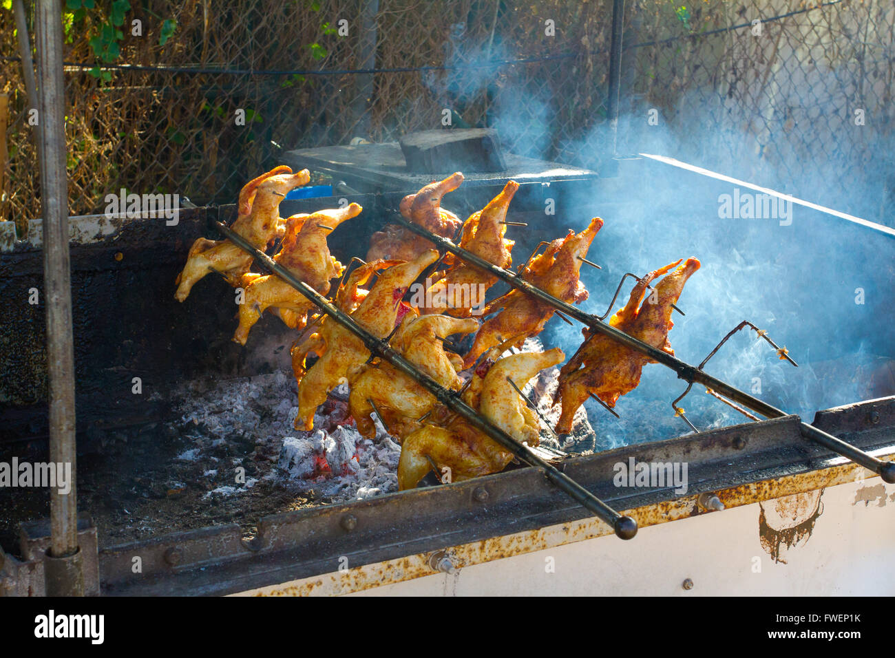Pollo barbeque viene cotta su un fuoco di legno con una rotisserie alle Hawaii per pranzo piastre. Foto Stock