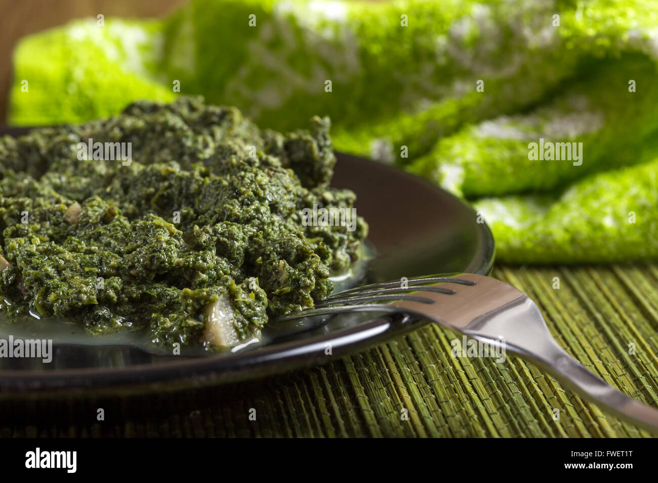 Stufati di ortiche con salsa di panna e aglio sulla piastra scuro con forca Foto Stock