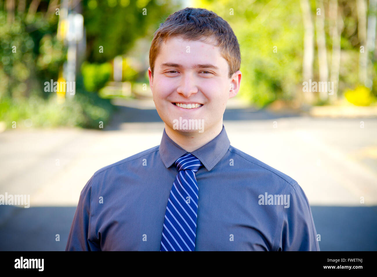 Uno studente di college business professional è fotografato esterno con luce naturale per creare un ritratto di una persona che indossa una gr Foto Stock