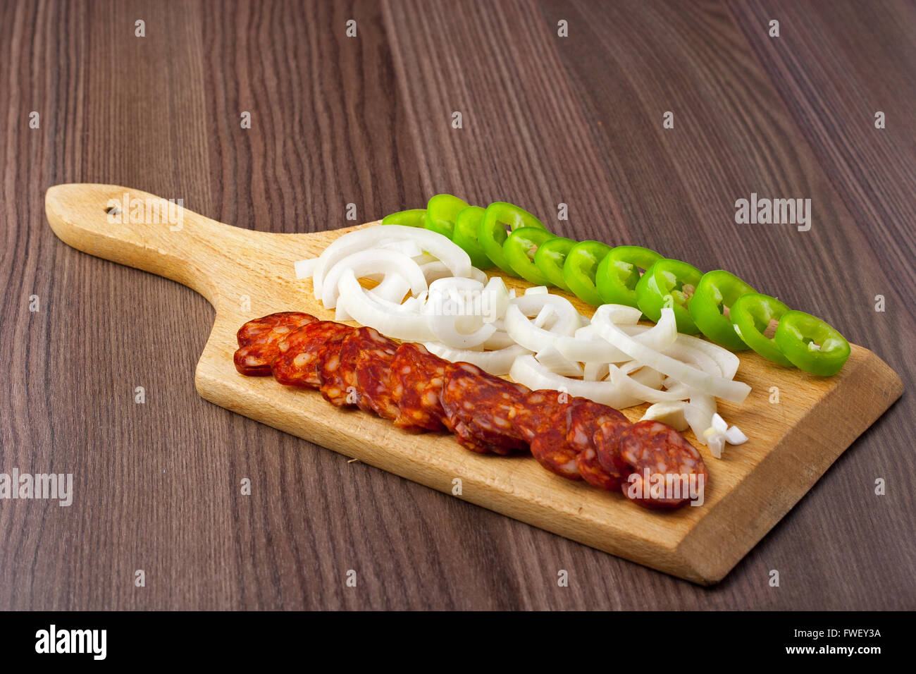 Ungherese piccante, affumicato, salsiccia. Servite su un piatto di legno con un po' di cipolla fresca e pepe verde Foto Stock