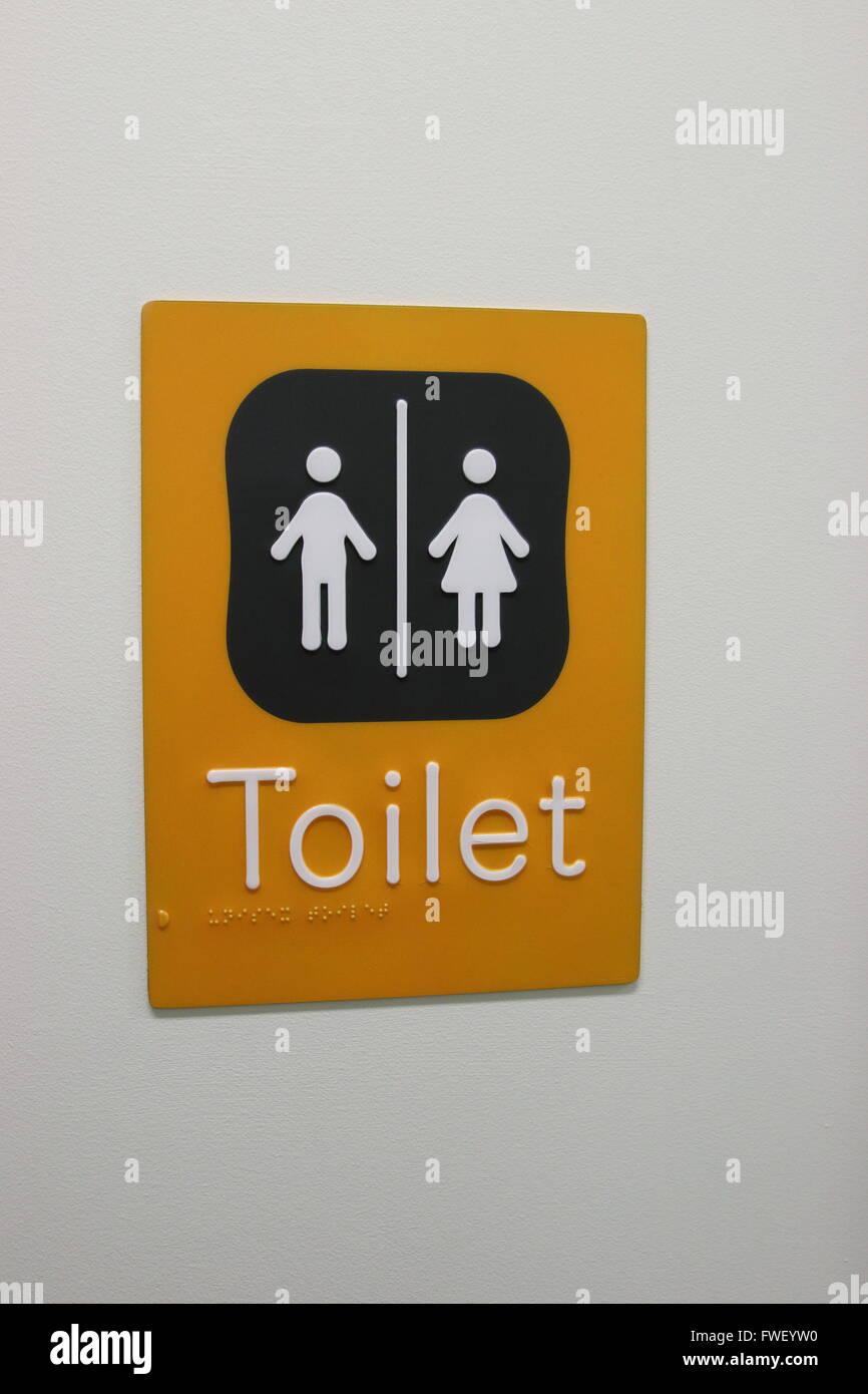 Servizi igienici pubblici cartello con scritto in braille e di immagine contro il muro Foto Stock