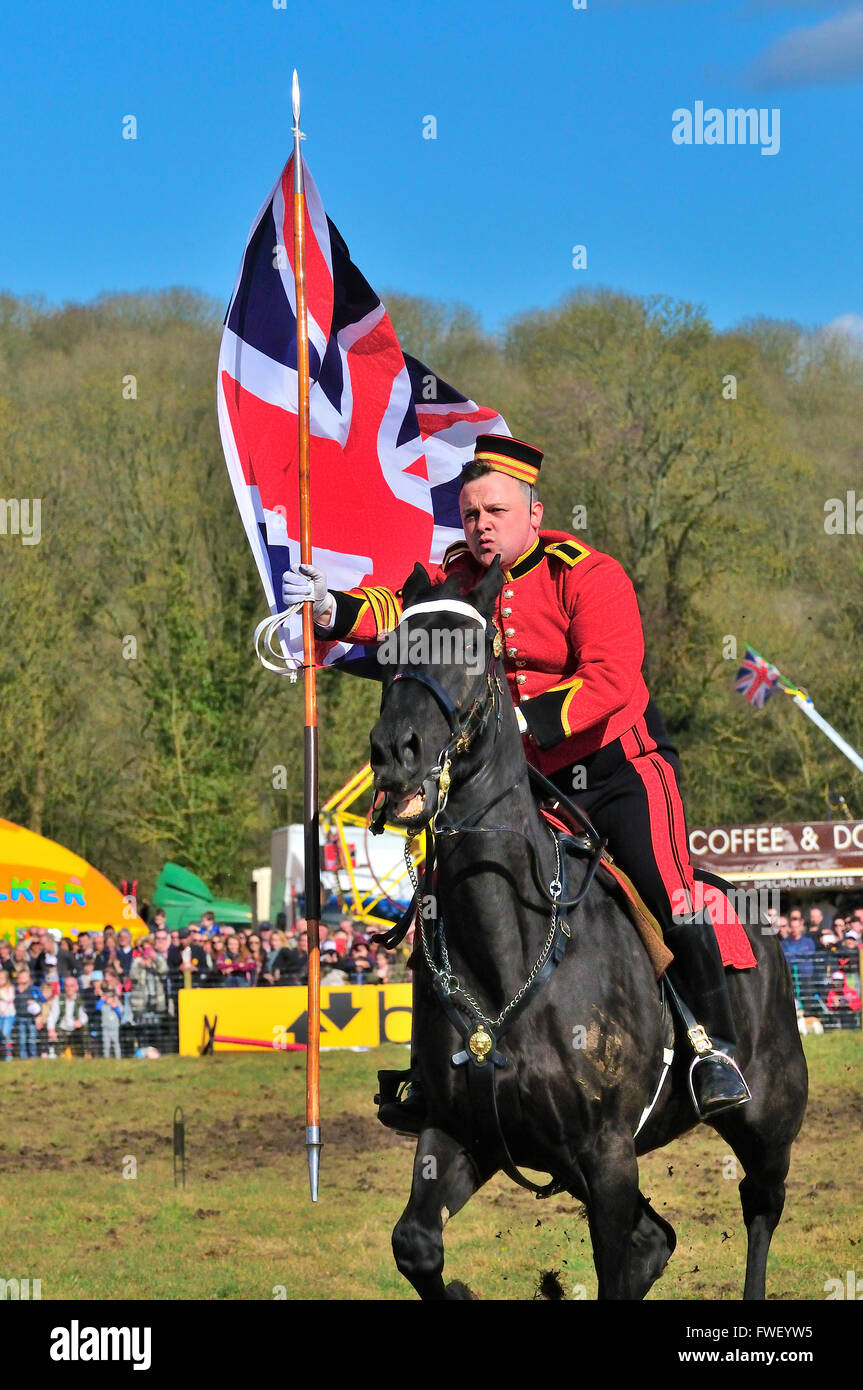 Domestico soldato di cavalleria la carica attraverso il quartiere fieristico con la bandiera europea durante il giro musicale della cavalleria della famiglia Foto Stock
