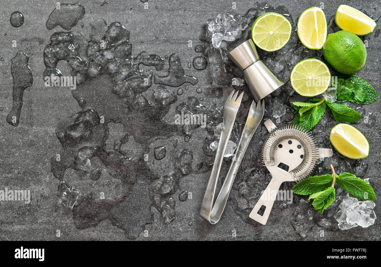 Cocktail di rendere gli strumenti e gli ingredienti con ghiaccio sulla pietra scura sullo sfondo Foto Stock