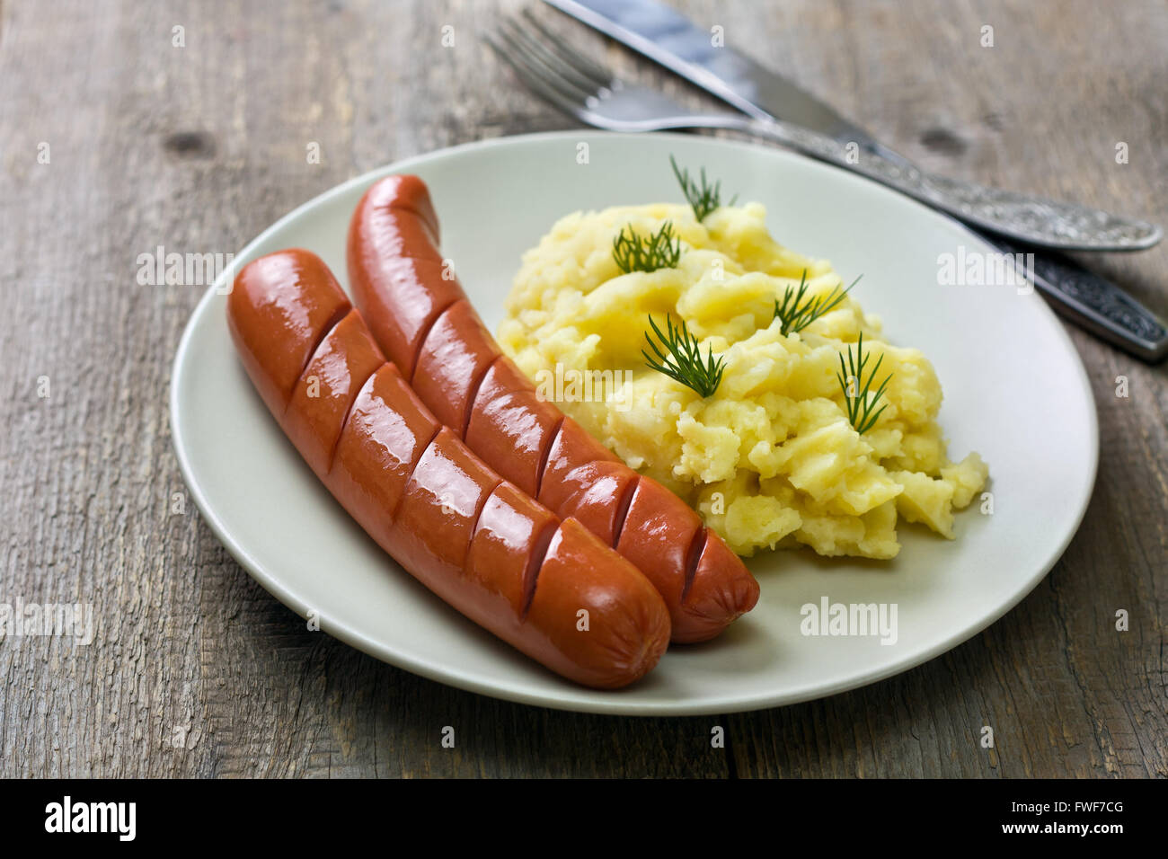 Purè di patate e salsicce sul vecchio sfondo di legno Foto Stock