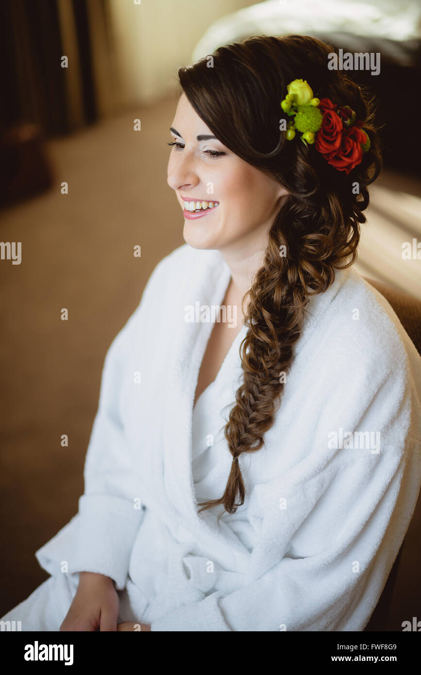 Sposa si siede su una sedia in tunica bianca Foto Stock