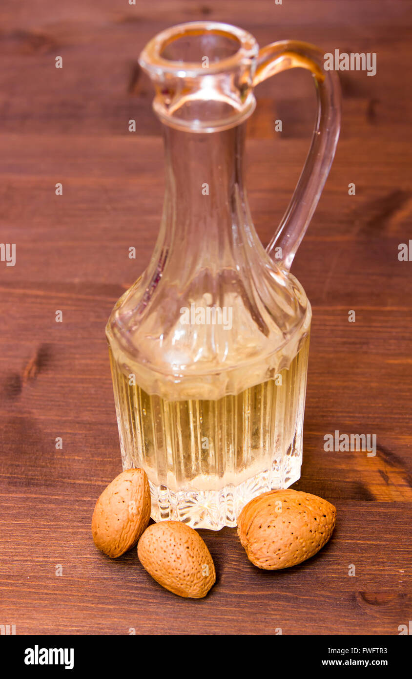 Bottiglia con olio di mandorle sul tavolo di legno Foto Stock