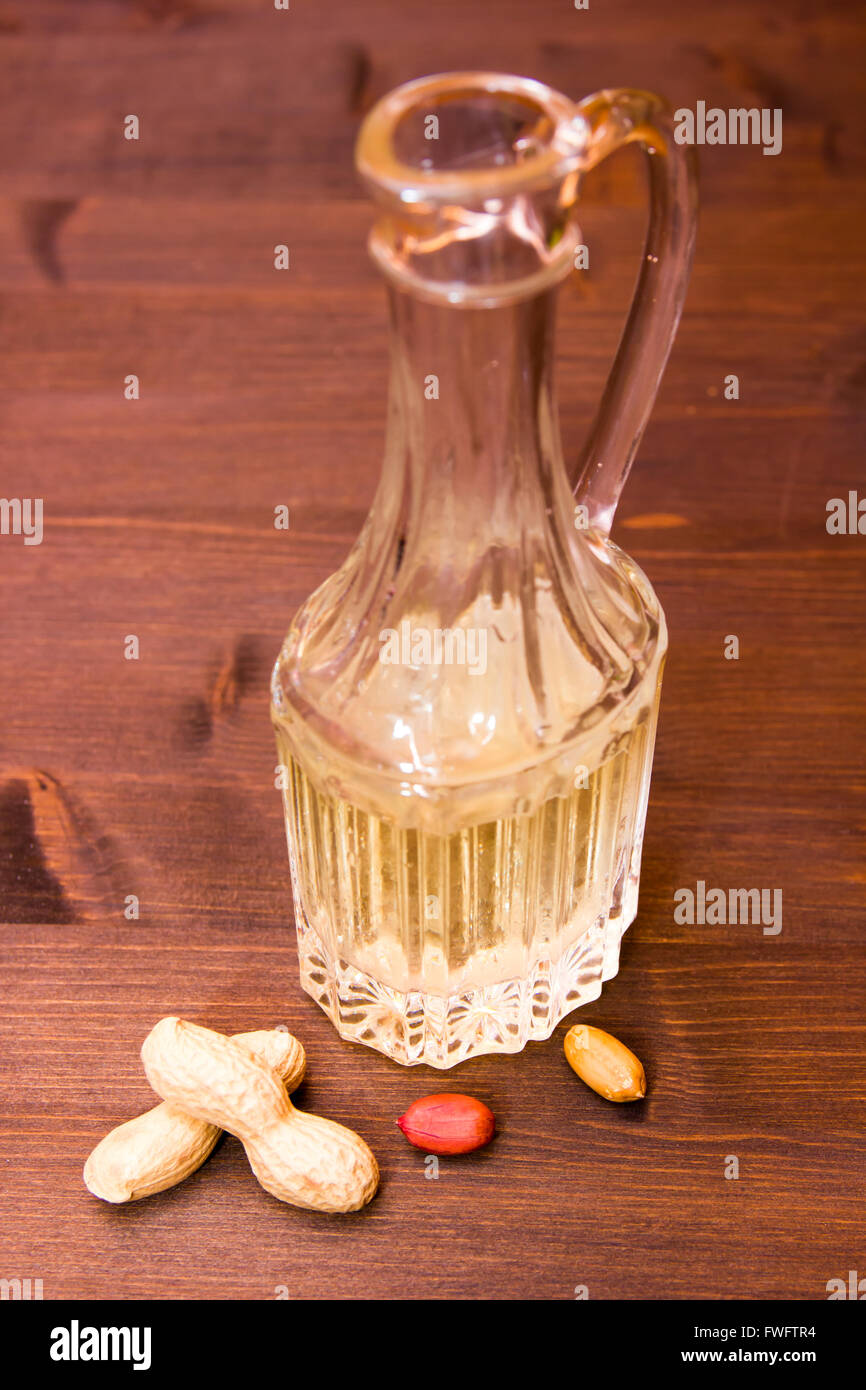 Bottiglia con olio di arachide sul tavolo di legno Foto Stock