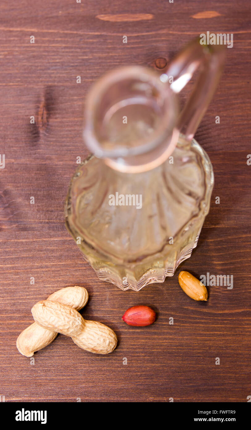 Bottiglia con olio di arachide sul tavolo in legno visto da sopra Foto Stock