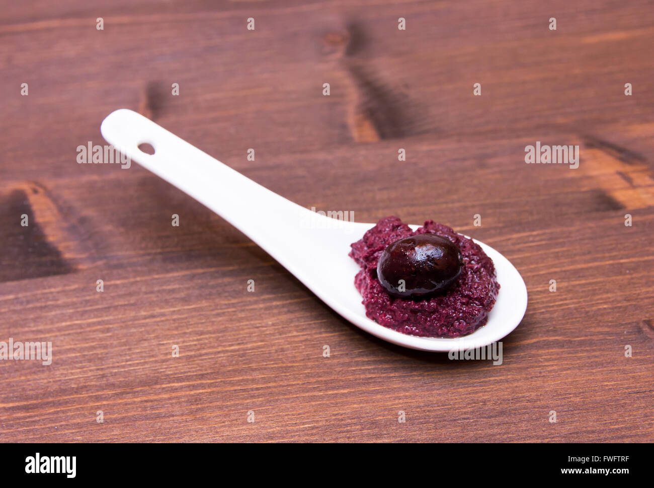 La pasta di olive sul cucchiaio sul tavolo di legno Foto Stock