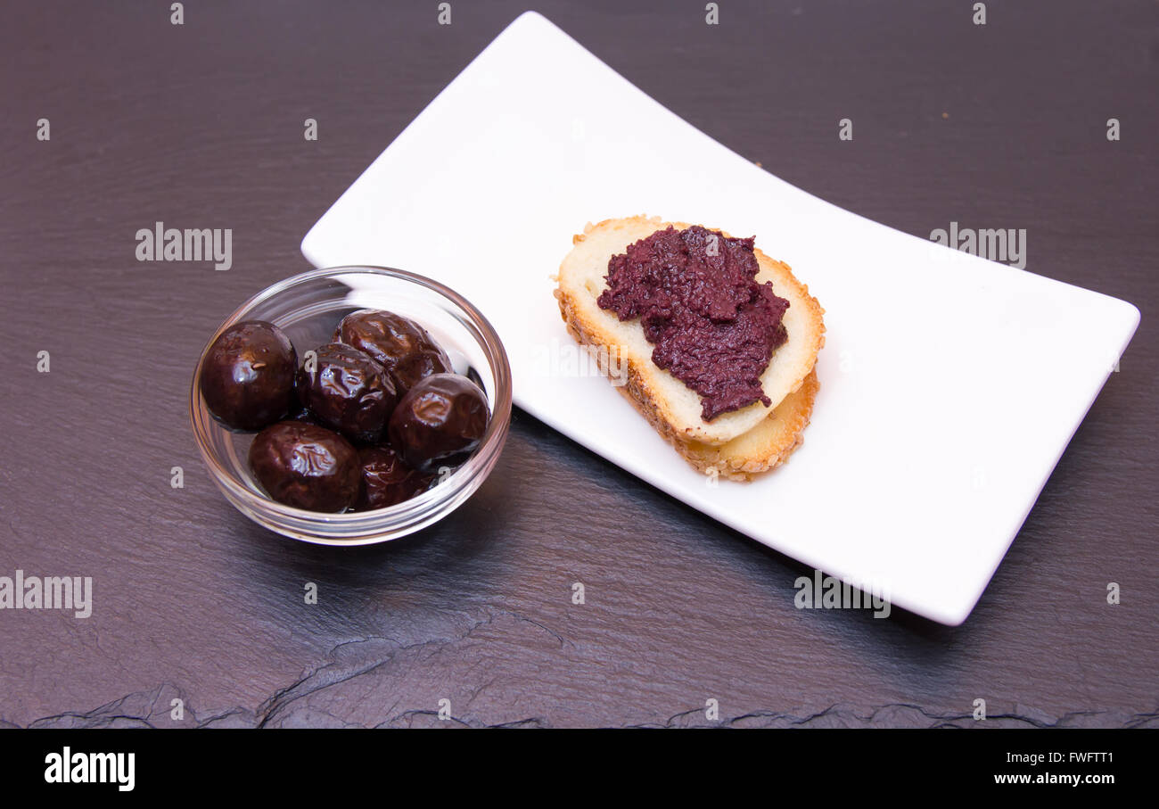 Fetta di pane con pasta di olive su top in ardesia Foto Stock