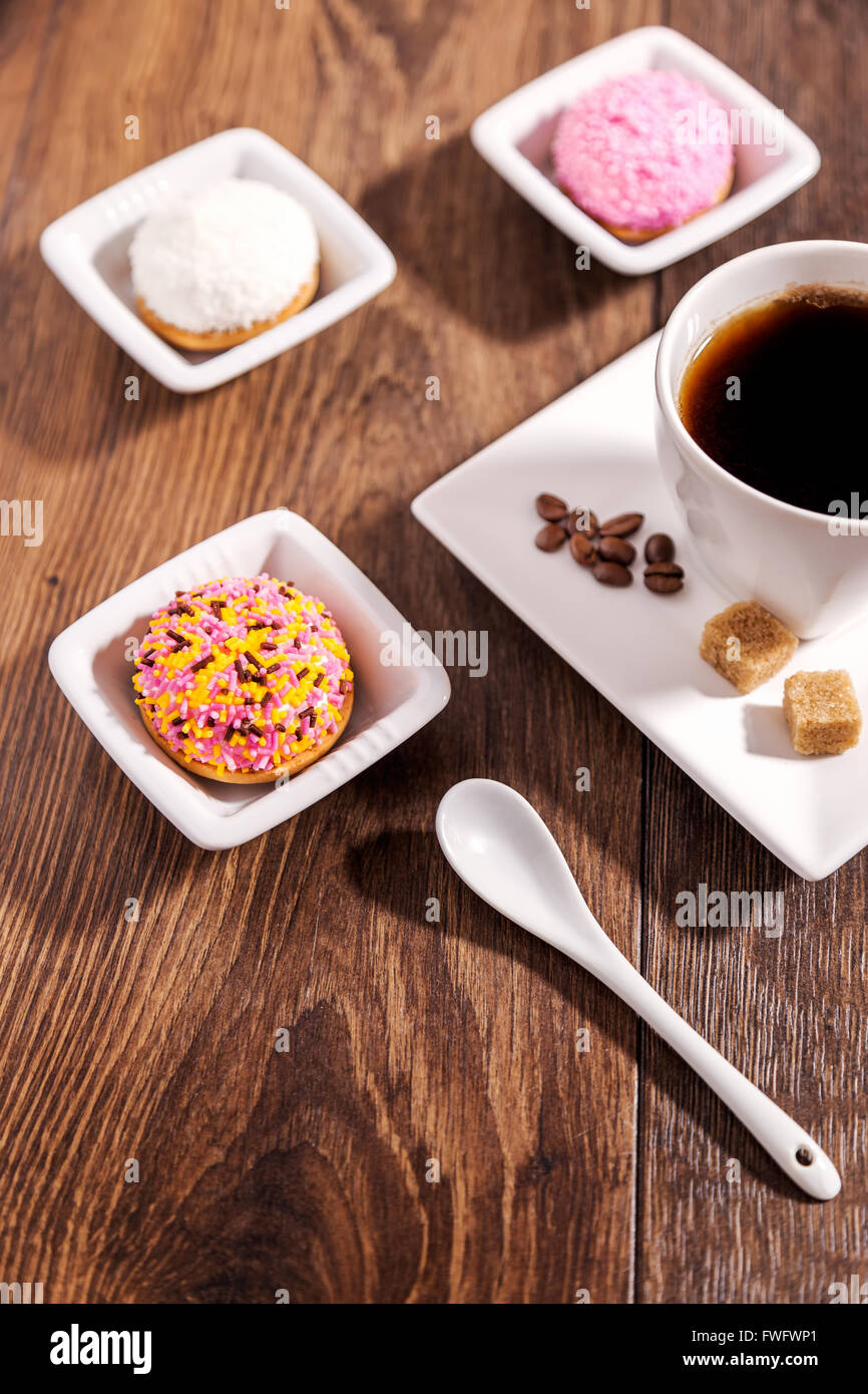 Tazza di caffè e biscotti di marshmallow con glassa di granuli colorati su bianco piattino in ceramica Foto Stock