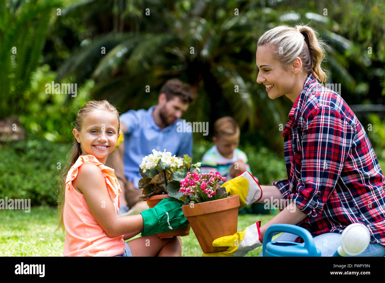 Madre di dare vaso di fiori alla figlia sorridente in cantiere Foto Stock