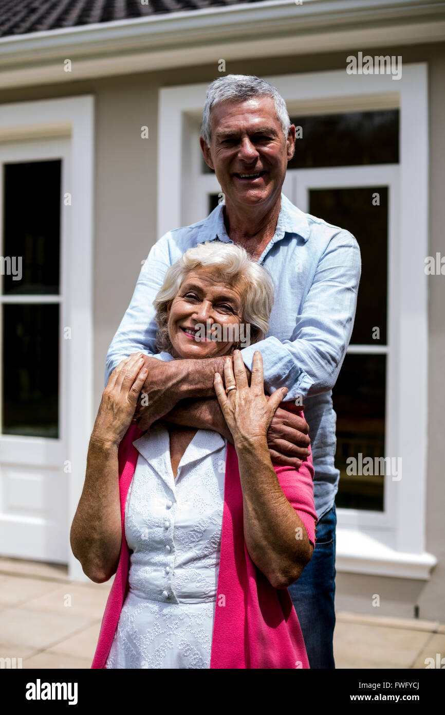 Sorridente coppia senior in piedi con le braccia intorno al cortile Foto Stock