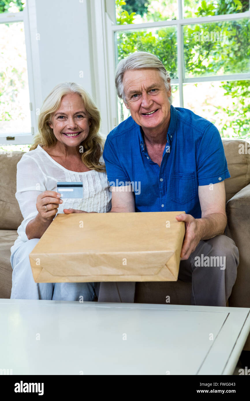 Felice coppia senior tenendo il pacco con smart card a casa Foto Stock