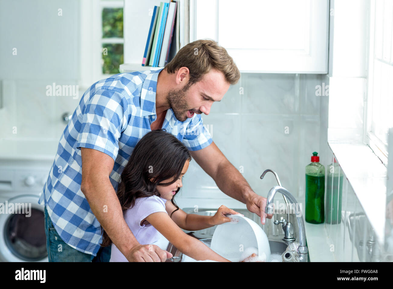 Figlia aiutando il padre nel lavaggio di utensili Foto Stock