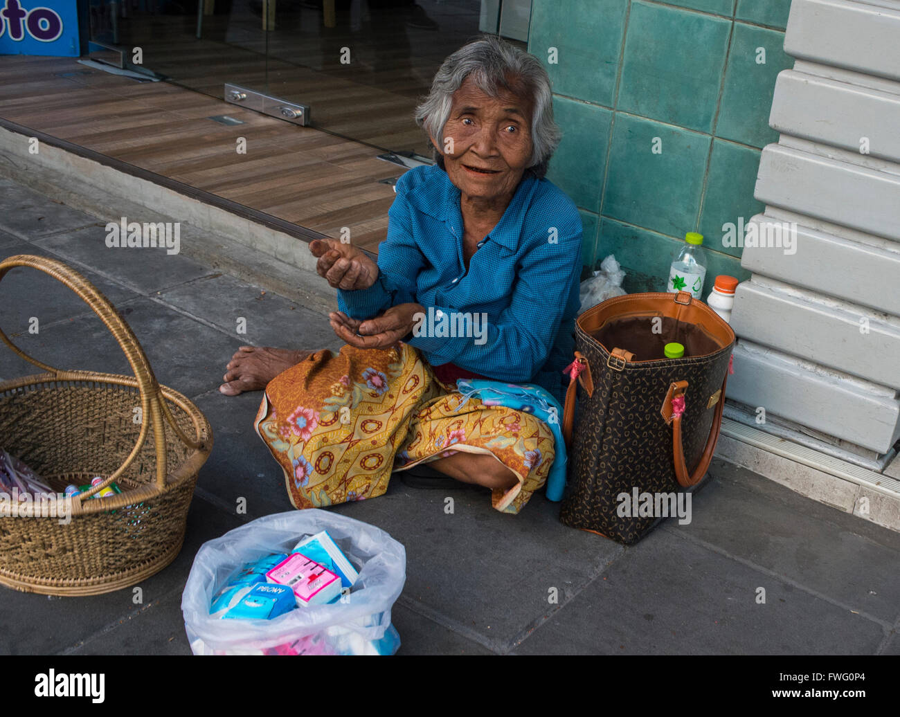Una donna anziana vive con la vendita di oggetti di piccole dimensioni e a mendicare per le strade di Bangkok, Thailandia Foto Stock