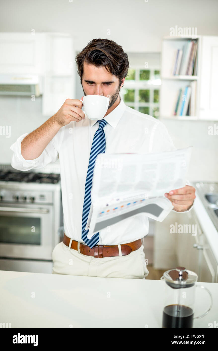 Imprenditore di bere il caffè durante la lettura del quotidiano a tabella Foto Stock