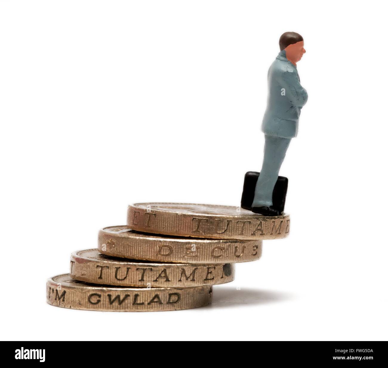 Una statuetta in miniatura imprenditore in piedi su una pila di libbra di monete. Foto Stock