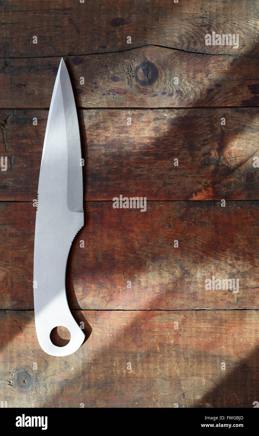Un coltello gettando sul bello sfondo di legno sotto il fascio di luce solare Foto Stock