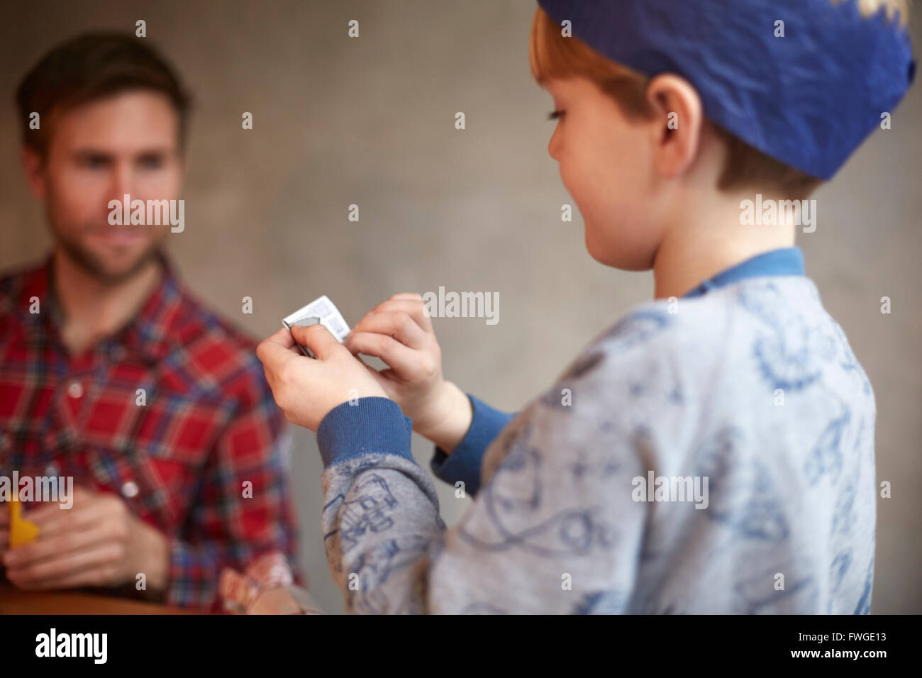 Un uomo e un bambino seduti a un tavolo da cucina la condivisione di un cracker scherzo. Foto Stock