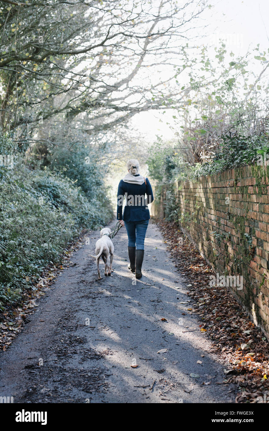 Una donna che cammina con un cane su un vicolo del paese. Foto Stock