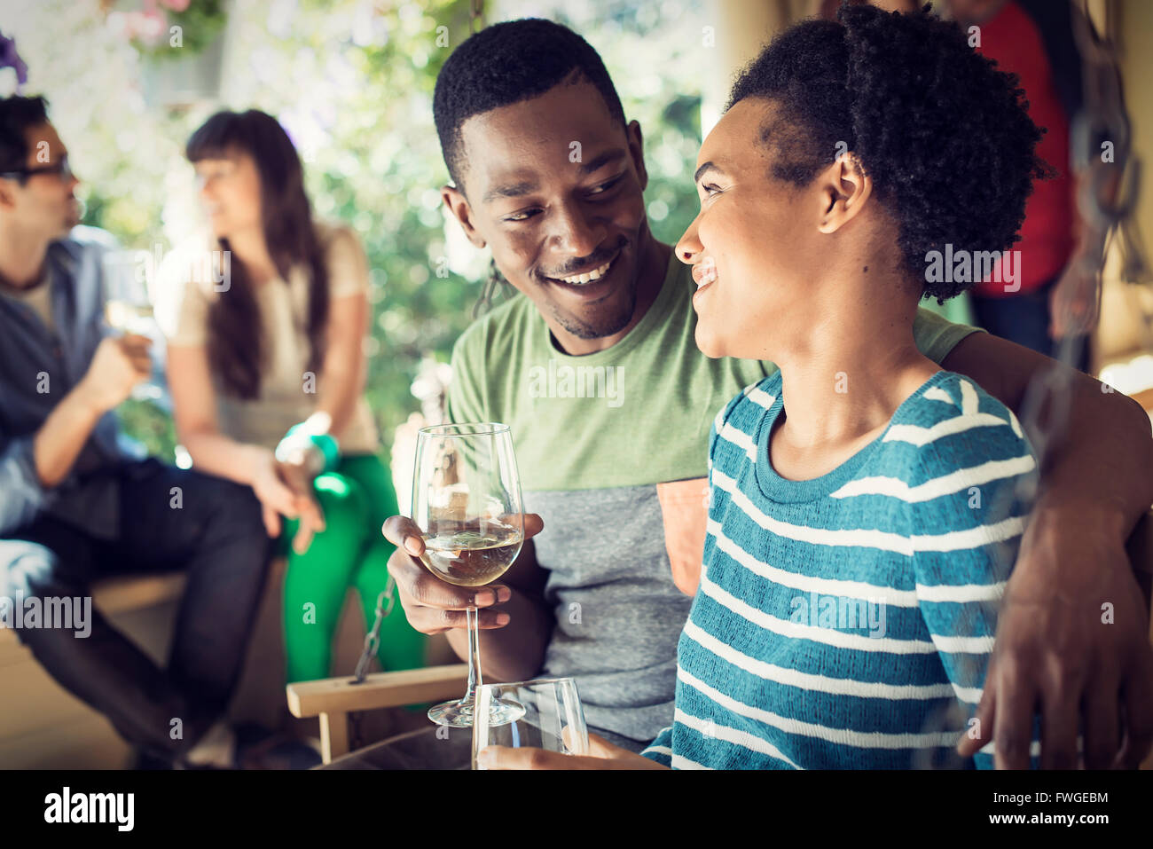 Un gruppo di amici, gli uomini e le donne a un house party, un paio di fianco a fianco. Foto Stock