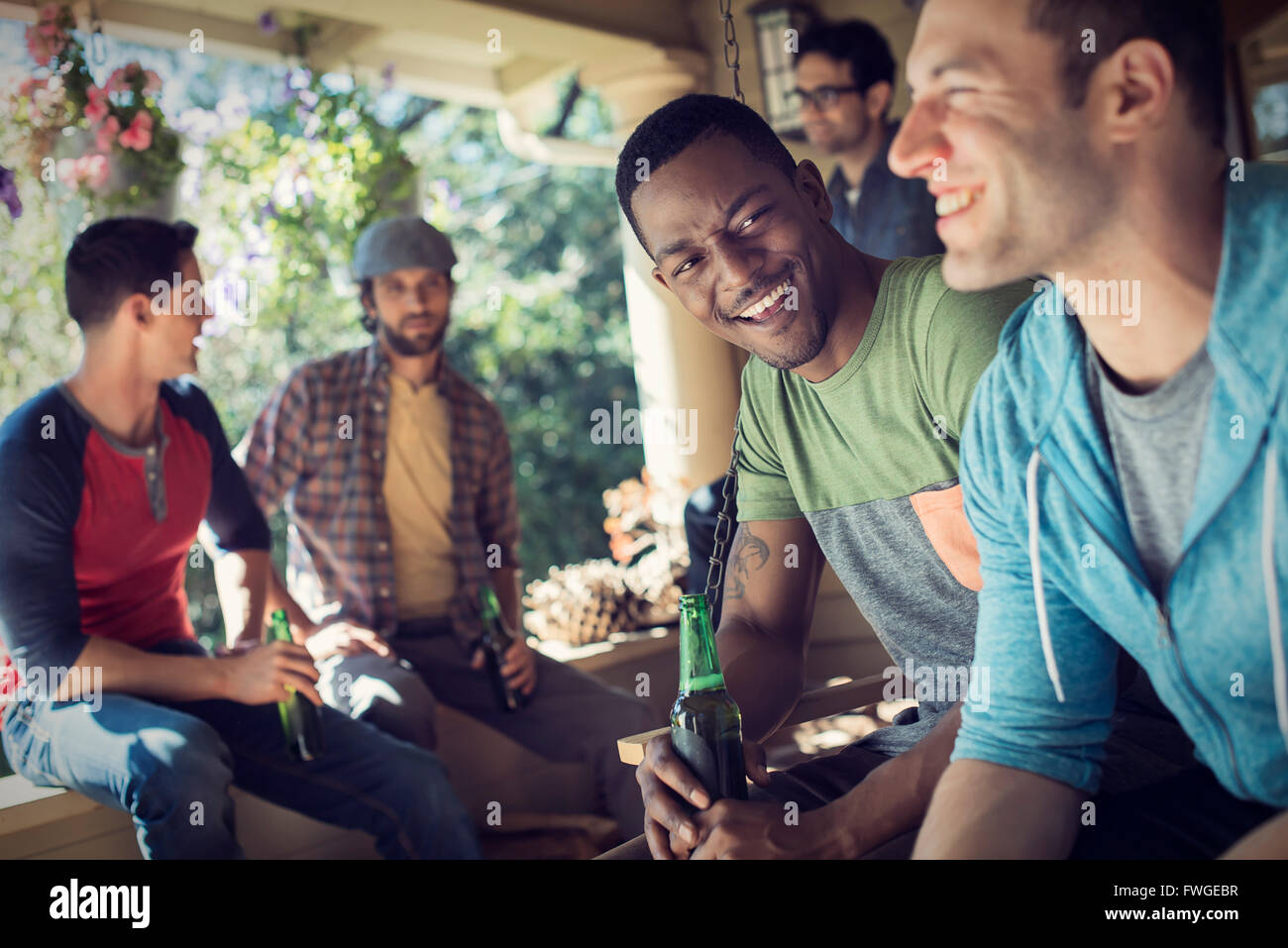 Un gruppo di amici, gli uomini e le donne a una festa. Due uomini ridere insieme. Foto Stock