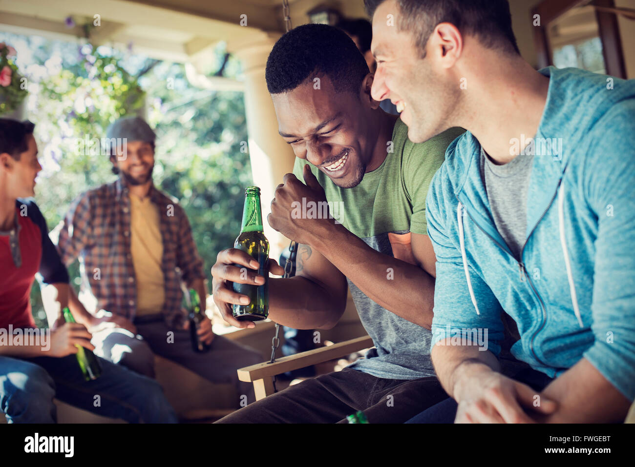 Un gruppo di amici, gli uomini e le donne a una festa. Due uomini a ridere. Foto Stock