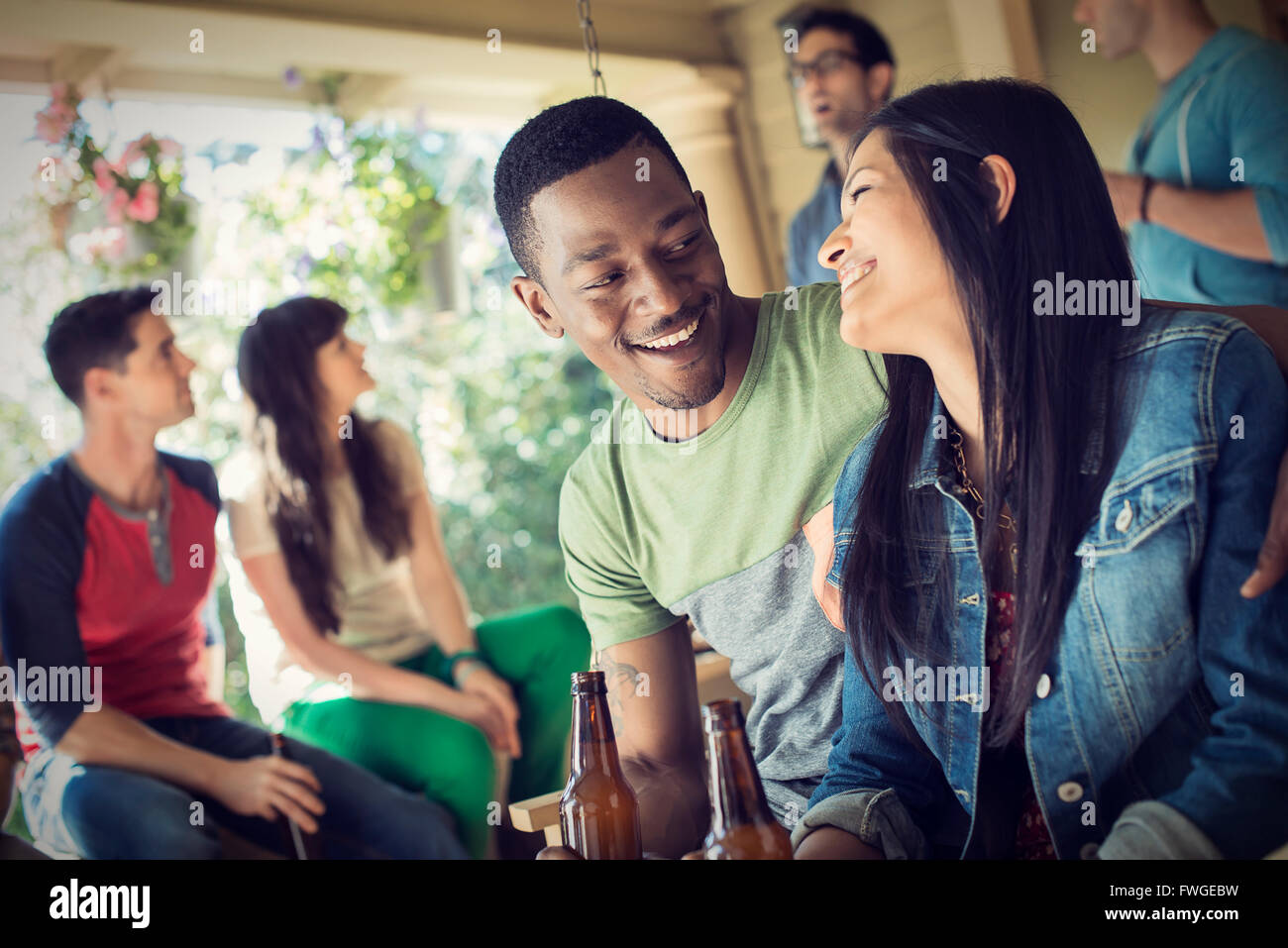 Un gruppo di amici, gli uomini e le donne a un house party di bere vino. Foto Stock