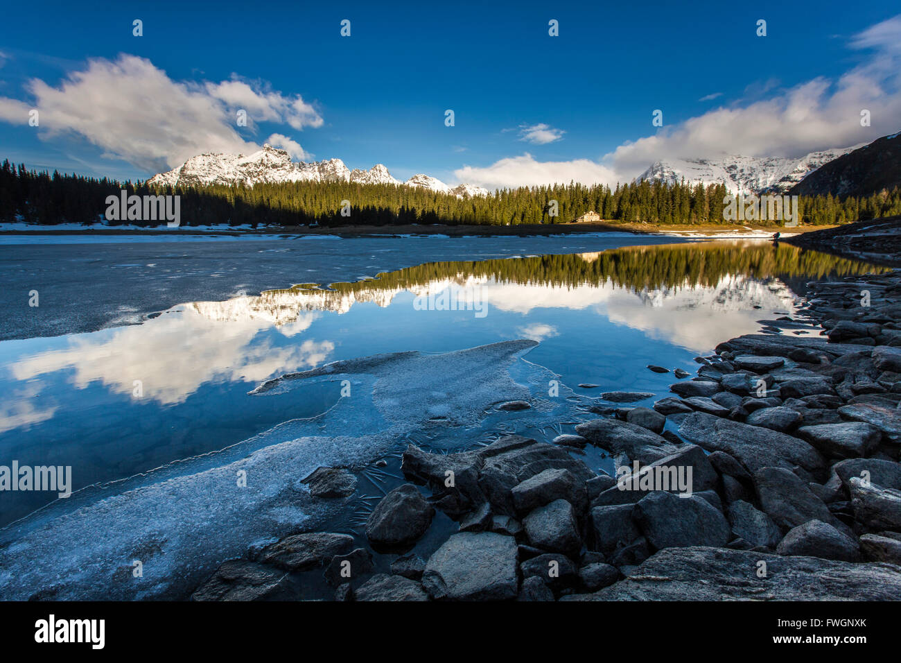 La molla del disgelo si scioglie il ghiaccio mentre vette innevate sono riflesse nel Lago Palu, Malenco Valley, Valtellina, Lombardia, Italia, Europa Foto Stock