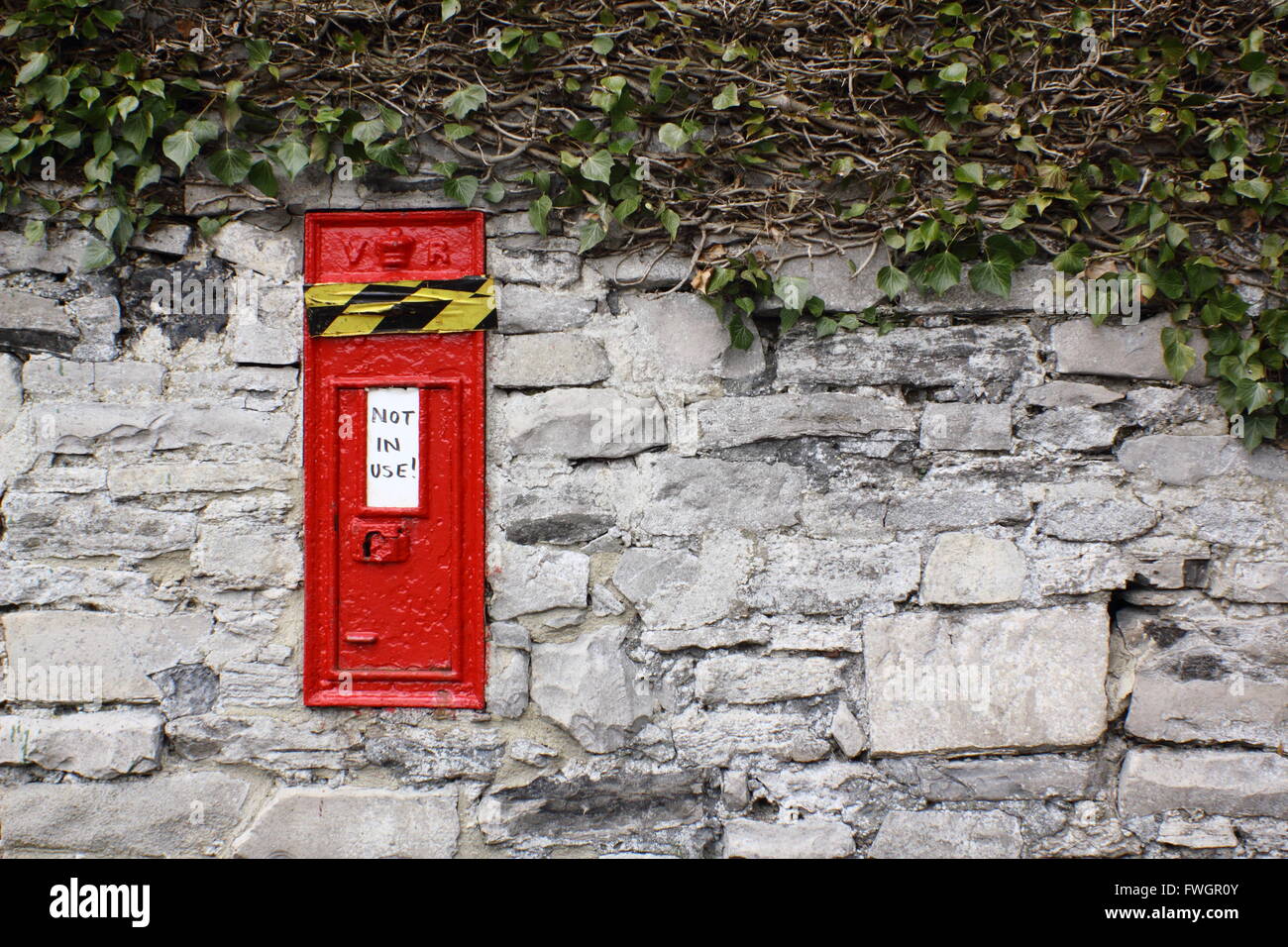 Un rosso post box set in una parete in un villaggio rurale nel Peak District National, Derbyshire è nastrata oltre e firmato "non in uso". Foto Stock